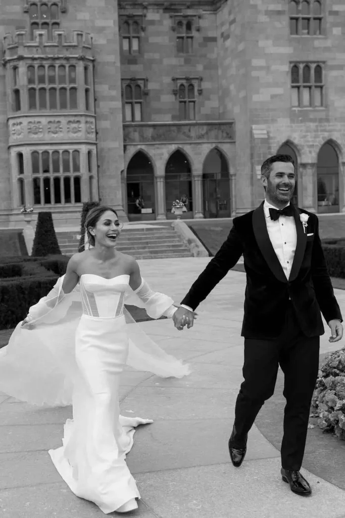 Destination wedding at Adare Manor, County Limerick — black and white portrait of the bride and groom holding hands and smiling outdoors on the estate grounds.