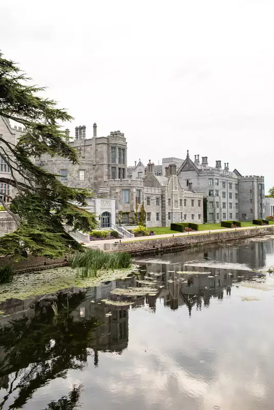 Destination wedding in Ireland at Adare Manor, County Limerick — exterior view of the manor with the lake visible in the foreground.
