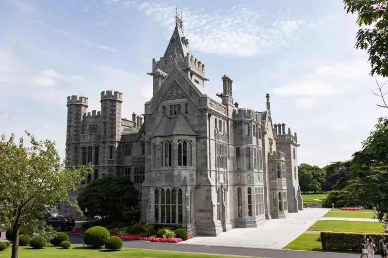 Destination wedding in Ireland at Adare Manor, County Limerick — exterior view of the manor house under a clear blue sky on a bright day.