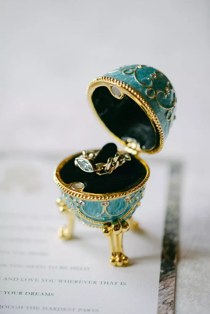 Destination wedding at Ashford Castle, County Mayo — ring detail presented in an ornate eggshell-shaped ring box with decorative detailing on the exterior during a styled wedding detail shot.