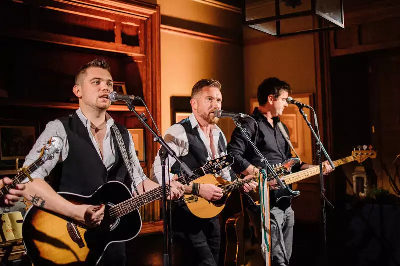 Destination wedding at Ballynahinch Castle, County Galway, Ireland — live entertainment during the wedding weekend with a band performing on stage, featuring musicians with instruments and microphones.