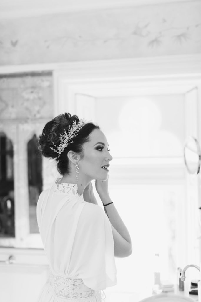 Destination wedding in Ireland at Ashford Castle, County Mayo — bride putting in her earring during morning wedding preparations in a quiet getting-ready moment before the ceremony.