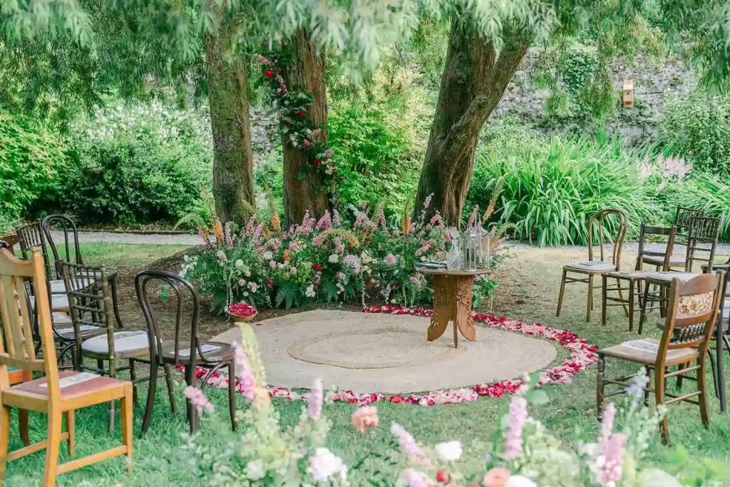 Destination wedding in Ireland at Ashford Castle, County Mayo — circular ceremony altar surrounded by flower petals beneath a large tree, with guest seating arranged around the outdoor setting.