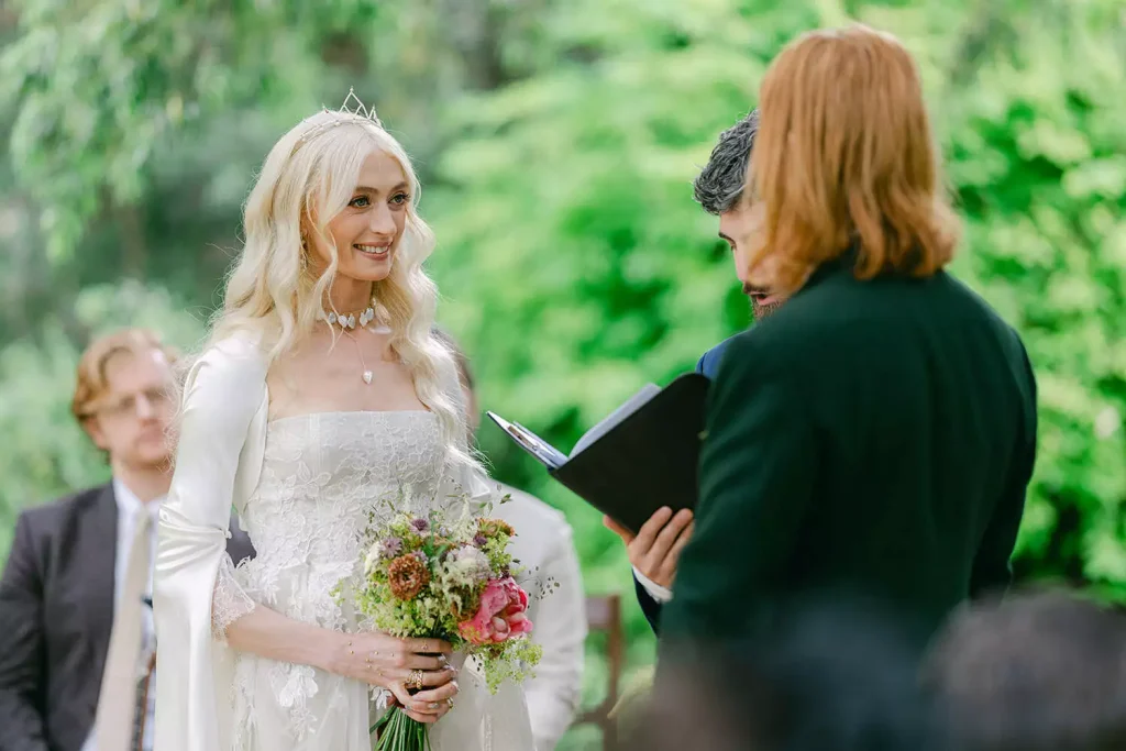 Destination wedding in Ireland at Ashford Castle, County Mayo — bride holding a floral bouquet while facing the groom at the altar during an outdoor wedding ceremony.