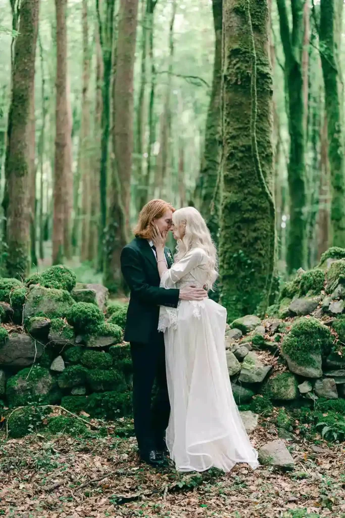 Destination wedding in Ireland at Ashford Castle, County Mayo — bride and groom embracing in a forest portrait, with the groom holding the bride at the waist as she cradles his face among the woodland surroundings.