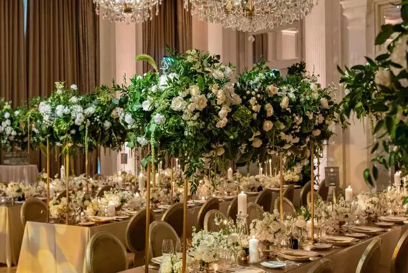 Irish destination wedding at Adare Manor, County Limerick — wedding dinner tables styled with large floral installations of white flowers and greenery throughout the reception space.