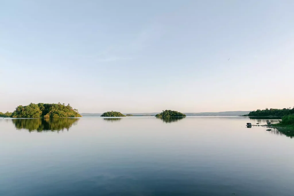 Irish destination wedding at Ashford Castle, County Mayo — view across Lough Corrib with a clear blue sky, calm water, and tree-covered islands on the horizon.