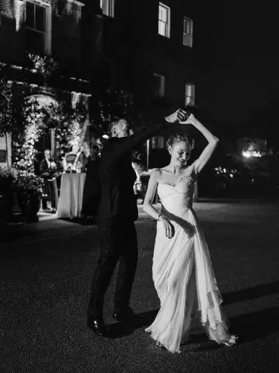 Irish destination wedding at Ballynahinch Castle, County Galway, Ireland — black-and-white portrait of the bride and groom dancing outdoors during the late-night party, with the groom spinning the bride beneath the evening lights.