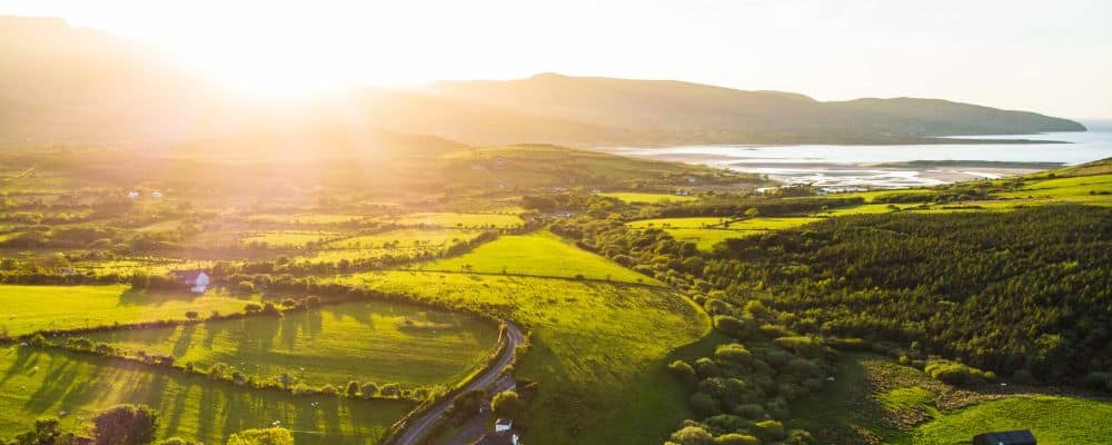 Drone shot overlooking Ireland countryside with coast view in the background.